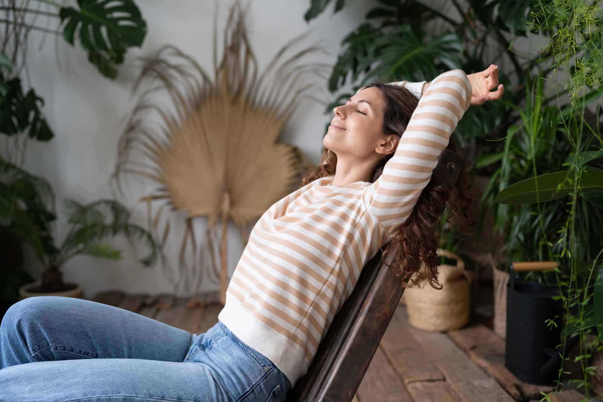 Relaxed woman stretching and smiling in a serene indoor space, reflecting Ascleus’s approach to stress relief and wellbeing.