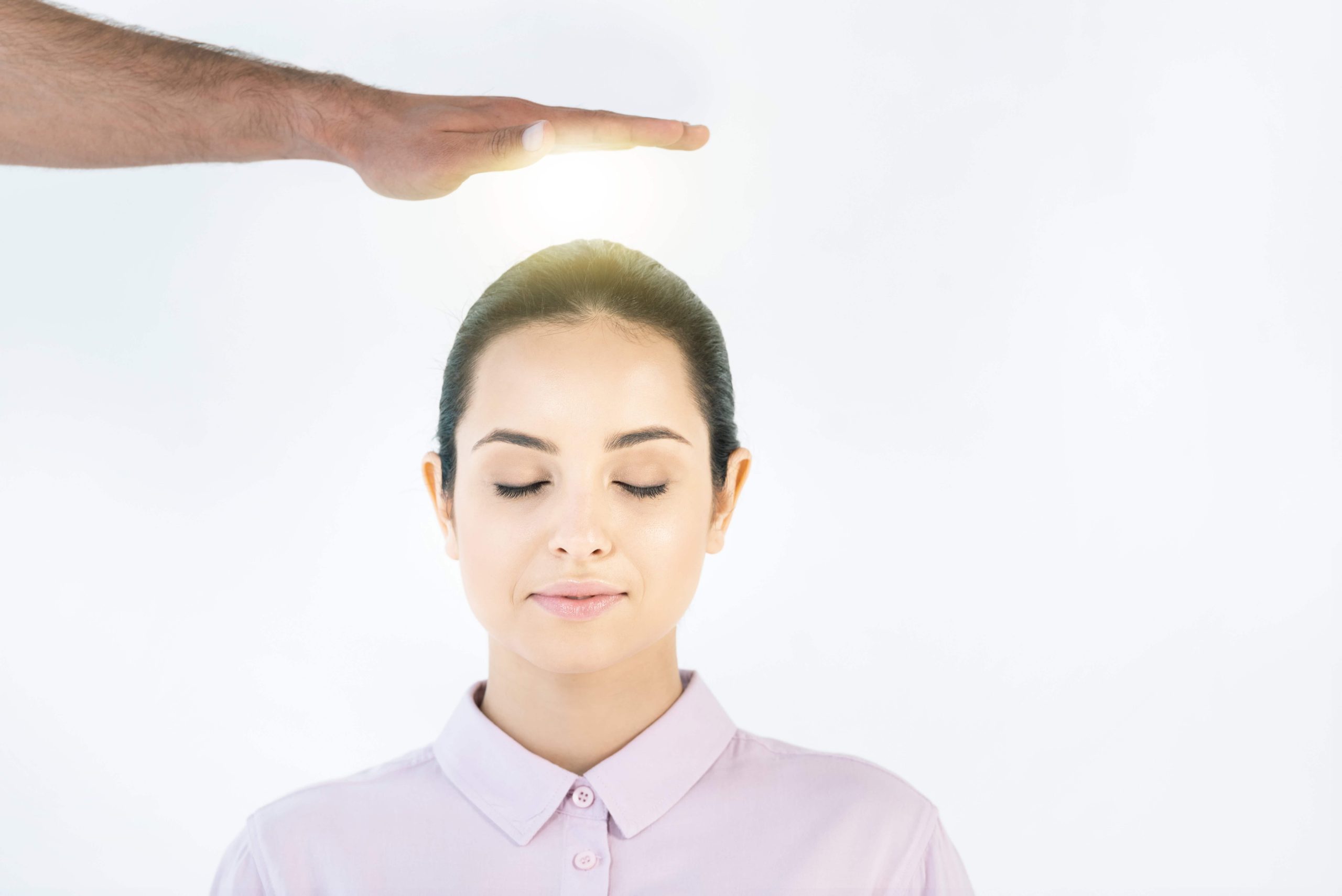 Energy healing session with soft glowing light above serene woman’s head, eyes closed in calm focus.